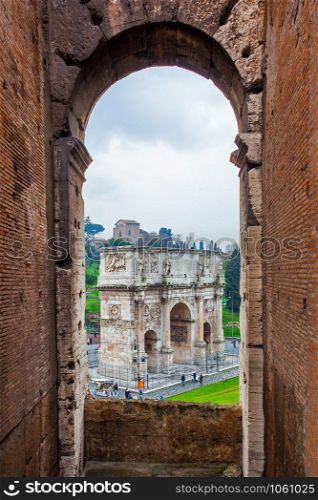 View to The Arch of Constantine through an archway of The Colosseum in Rome, Italy