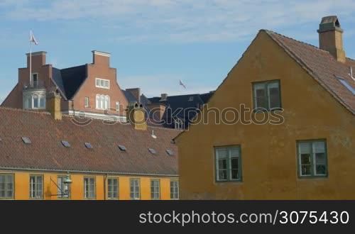 View to the house roofs and worn building in foreground on blue sky background