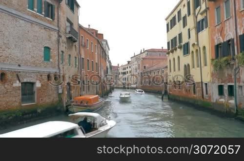 View to the narrow canal in Venice. Motor boats sailing among the old worn houses. Traveling in Europe, Italy