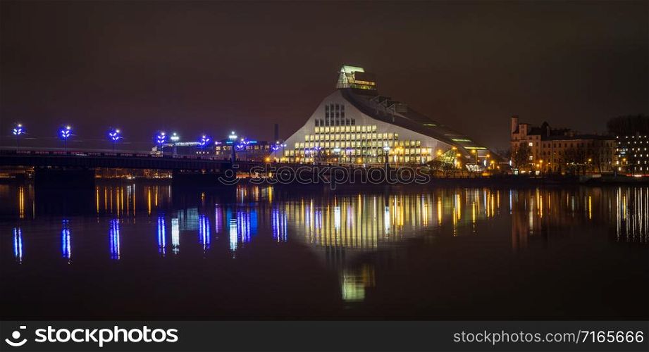View to the National Library of Latvia next to the bridge in the evening with beautiful reflections in Daugava river