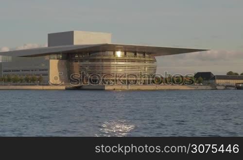 View to the The Copenhagen Opera House located at the shore of the harbour, cutter sailing by. It is one of the most modern and expensive opera houses