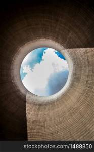 View up a coal burning power plant cooling tower with clouds and sunshine