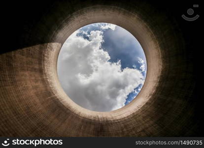 View up a coal burning power plant cooling tower with clouds and sunshine