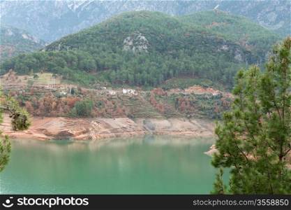Views of the azure mountain lake through the pine forest