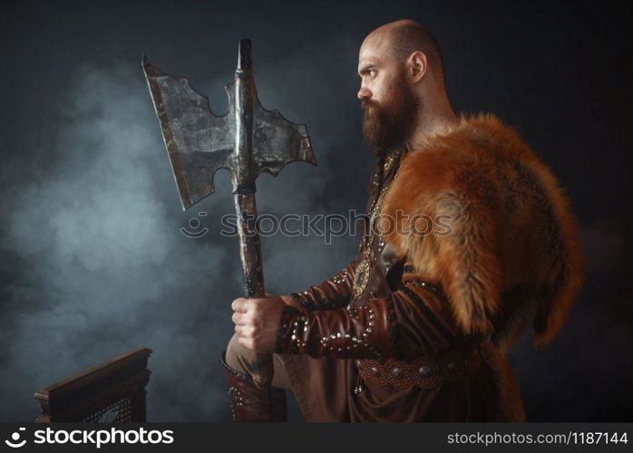 Viking with axe, martial spirit, barbarian image, side view. Ancient warrior in smoke on dark background