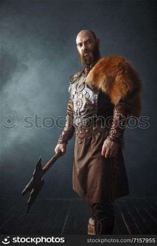 Viking with axe, martial spirit, barbarian image, side view. Ancient warrior in smoke on dark background. Viking with axe, barbarian, side view