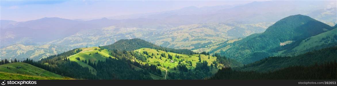 Village is in the mountains on green meadows. Summer landscape. Panorama. Village is in the mountains on green meadows