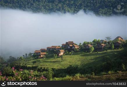 village thailand with foggy landscape mountains misty forest with tree and house in the moring winter nature / View of foggy house on hill countryside