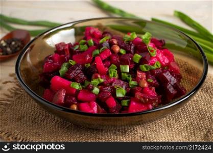 Vinaigrette on a wooden background. Russian vegetable salad with red beets in a bowl. Rustic style, traditional dish.. Vinaigrette on a wooden background. Russian vegetable salad with beets in a bowl.