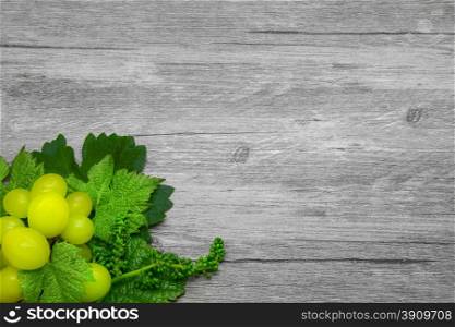 Vine leaves and grapes on a gray wooden background.