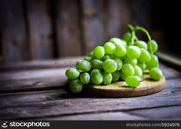 Vine of green grapes on rustic wooden background