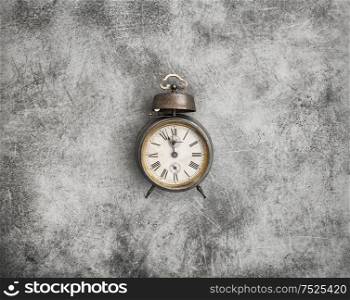 Vintage alarm clock on dark stone background. Five to twelve