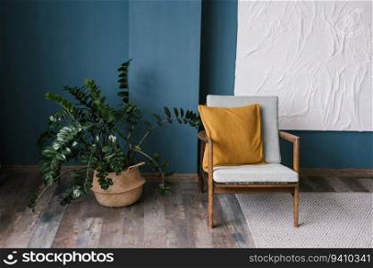 Vintage armchair with a yellow cushion against a blue wall in the living room. Indoor plant zamiokulkas in a wicker pot