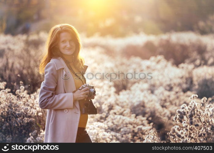 vintage autumn. girl with a vintage camera walks in the fields of fluffy dandelions at sunset