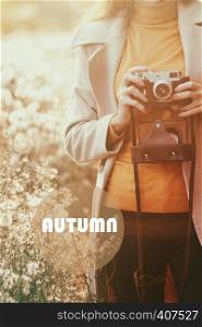 vintage autumn. girl with a vintage camera walks in the fields of fluffy dandelions at sunset
