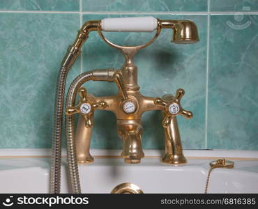 Vintage bath taps, golden tap with a green wall