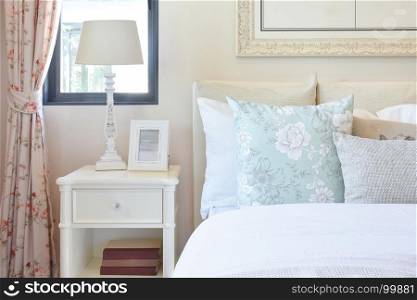 vintage bedroom interior with reading lamp and picture frame on white bedside table