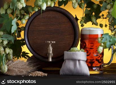 Vintage beer barrel with beer glass and fresh hops, with barley on wooden table still life