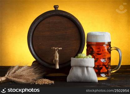 Vintage beer barrel with beer glass and fresh hops, with wheat on wooden table still life