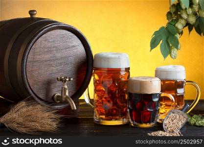Vintage beer barrel with beer glasses on wooden table with wheat bunch, hop and barley, still life with copy space