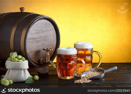 Vintage beer barrel with two beer glasses and bag full of fresh hops, with metal scoop with barley on wooden table still life, copy space