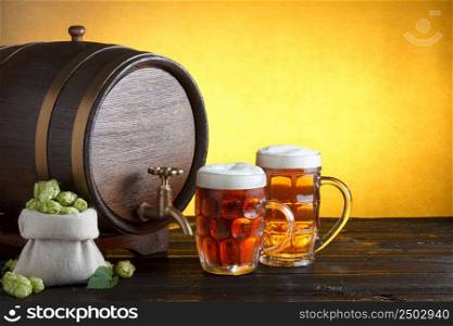 Vintage beer barrel with two beer glasses and burlap bag with fresh hops on wooden table still life with copy space