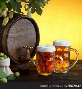 Vintage beer barrel with two beer glasses and frame of fresh hops on wooden table still life, copy space