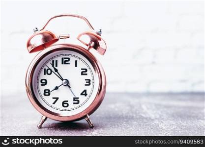 Vintage bell alarm clock on blurred white brick background with copy space for time management concept