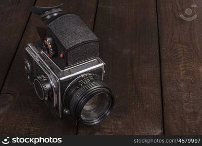 vintage black film camera on the brown background of natural wood with the lens