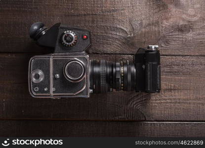 vintage black film camera on the brown background of natural wood with the lens