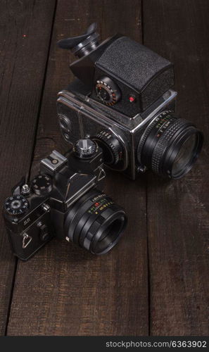 vintage black film camera on the brown background of natural wood with the lens