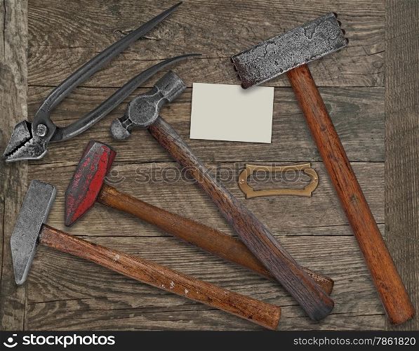 vintage blacksmith or metalwork tools over wooden bench, blank plate and business card for your text