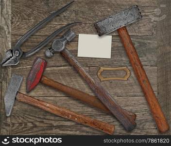 vintage blacksmith or metalwork tools over wooden bench, blank plate and business card for your text