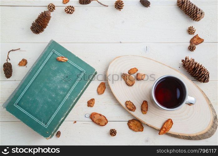 vintage book and drink in retro mug on wooden background. top view with space for text