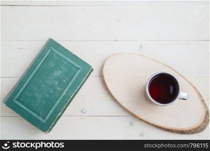vintage book and drink in retro mug on wooden background. the view from the top