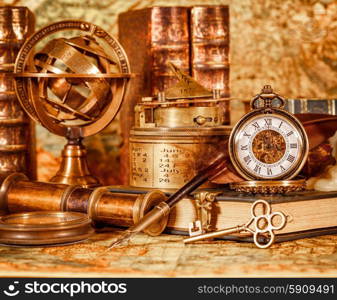 Vintage book, compass, telescope and a pocket watch lying on ancient world map in 1565.