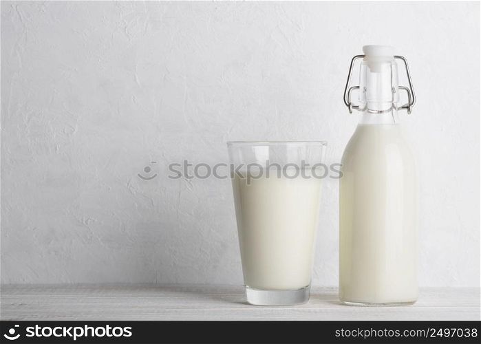 Vintage bottle of milk and glass of milk on white wooden table background