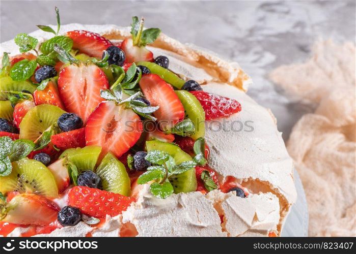 Vintage cake stand with Meringue dessert Pavlova with sugar powder, fresh strawberries, kiwi, blueberries and mint. Homemade baking.