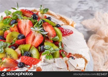 Vintage cake stand with Meringue dessert Pavlova with sugar powder, fresh strawberries, kiwi, blueberries and mint. Homemade baking.