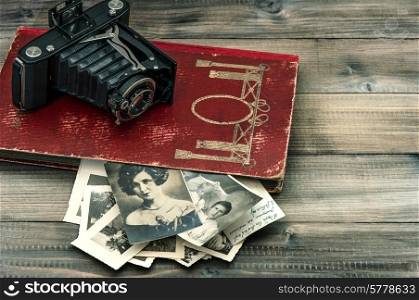 vintage camera and album with old photos on wooden table