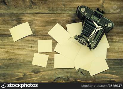 vintage camera and old photos on wooden background. nostalgic style picture