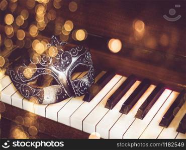 Vintage carnival mask on the background of piano keys. Top view, closeup. Carnival mask on the background of piano keys