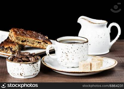 Vintage ceramic cup of coffee, coffee beans, cane sugar and a piece of chocolate cake