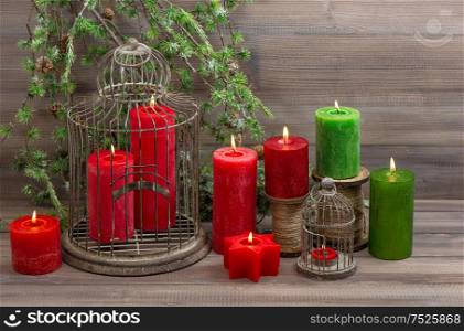 Vintage christmas decoration red burning candles and green pine branch on wooden background