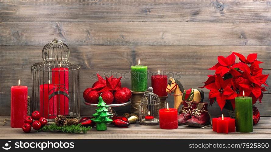 vintage christmas decoration with burning candles, antique baby shoes, red flower poinsettia, stars and baubles. Retro style toned picture