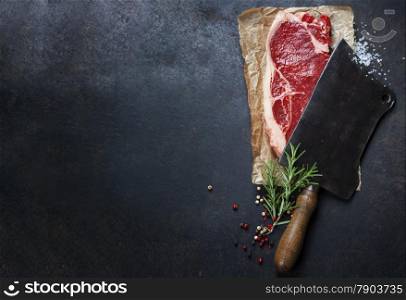 vintage cleaver and raw beef steak on dark background