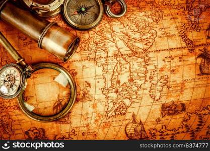 Vintage compass, magnifying glass, pocket watch, quill pen on an old ancient map in 1565. Vintage still life.