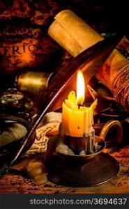 Vintage compass, magnifying glass, quill pen, spyglass lie on an old ancient map with a lit candle
