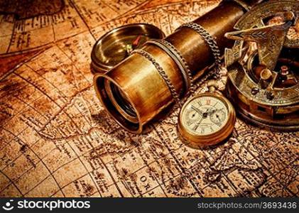Vintage compass, , spyglass and a pocket watch lying on an old map.