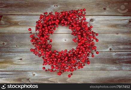 Vintage concept of a red berry holiday wreath on rustic wood